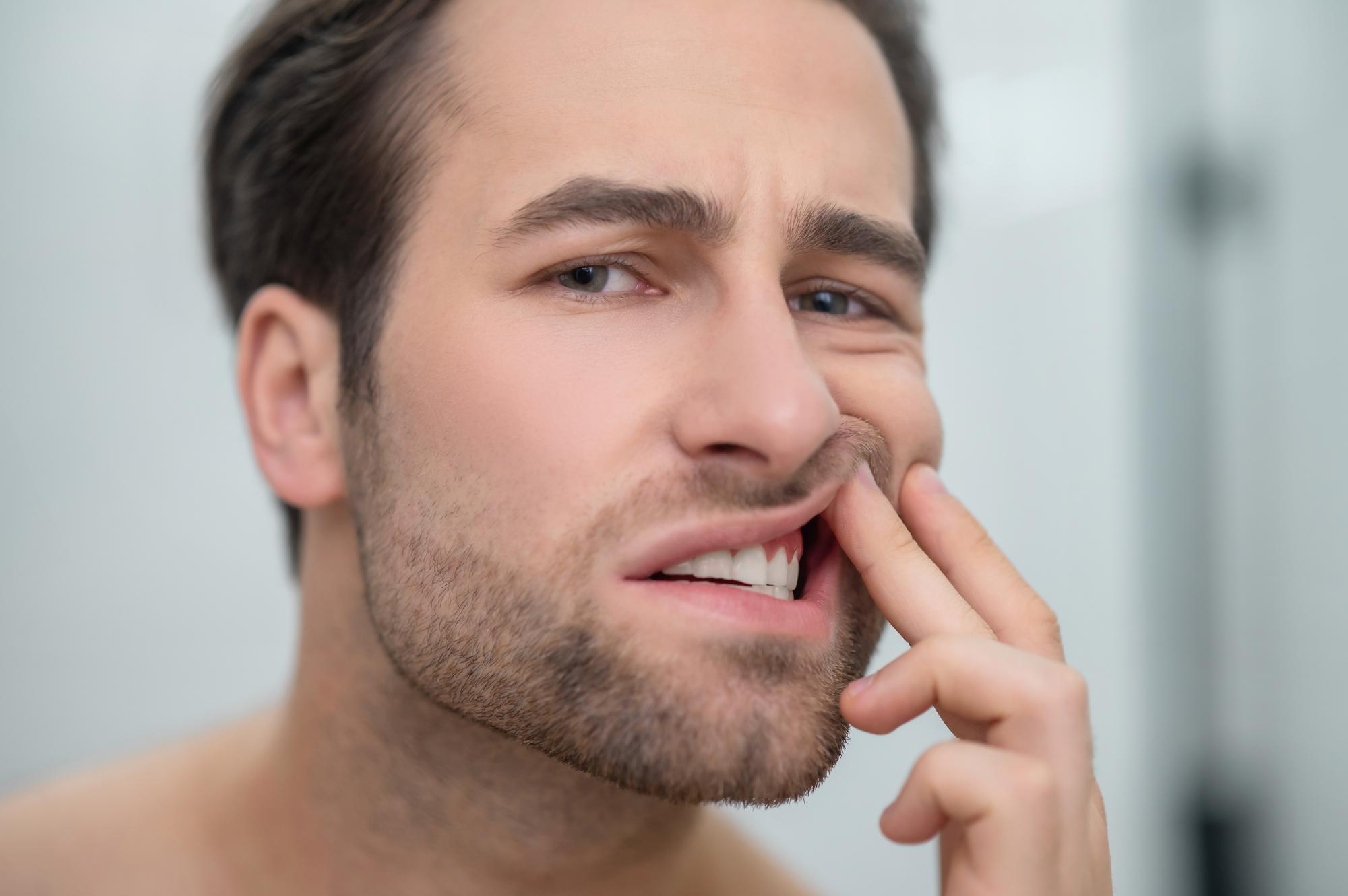 problemas-dentales-hombre-revisando-sus-dientes-mirando-perturbado